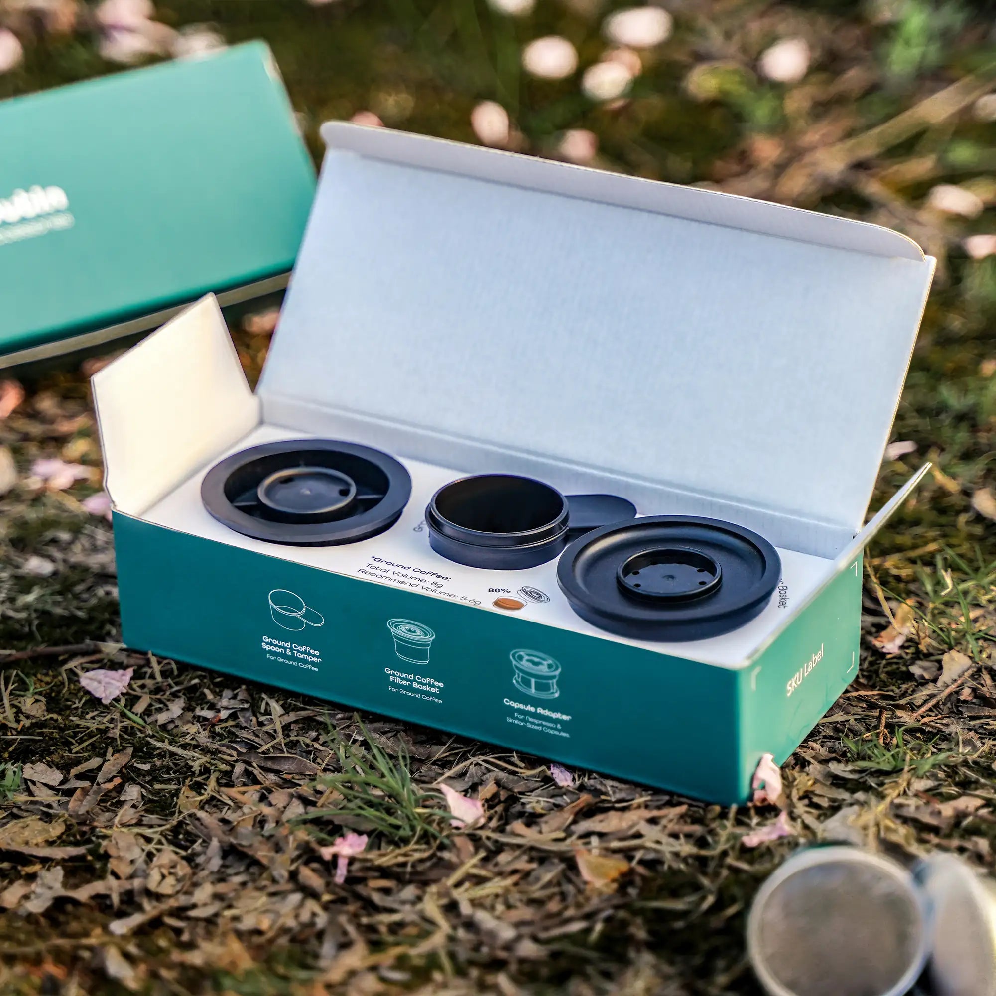 Outin Nano espresso kit with capsule adapter, ground coffee filter, and spoon in teal box.