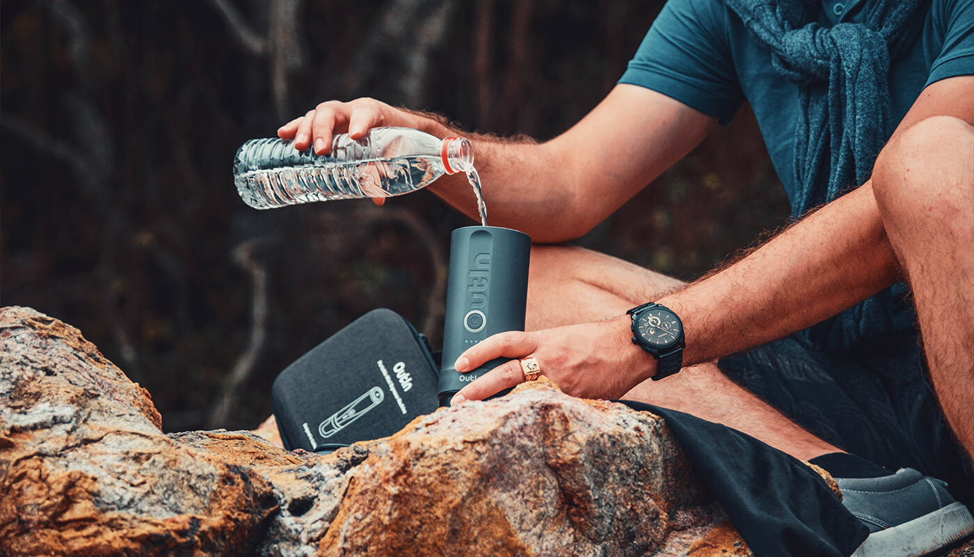 Preparing coffee outdoors with Outin portable espresso maker and branded case.