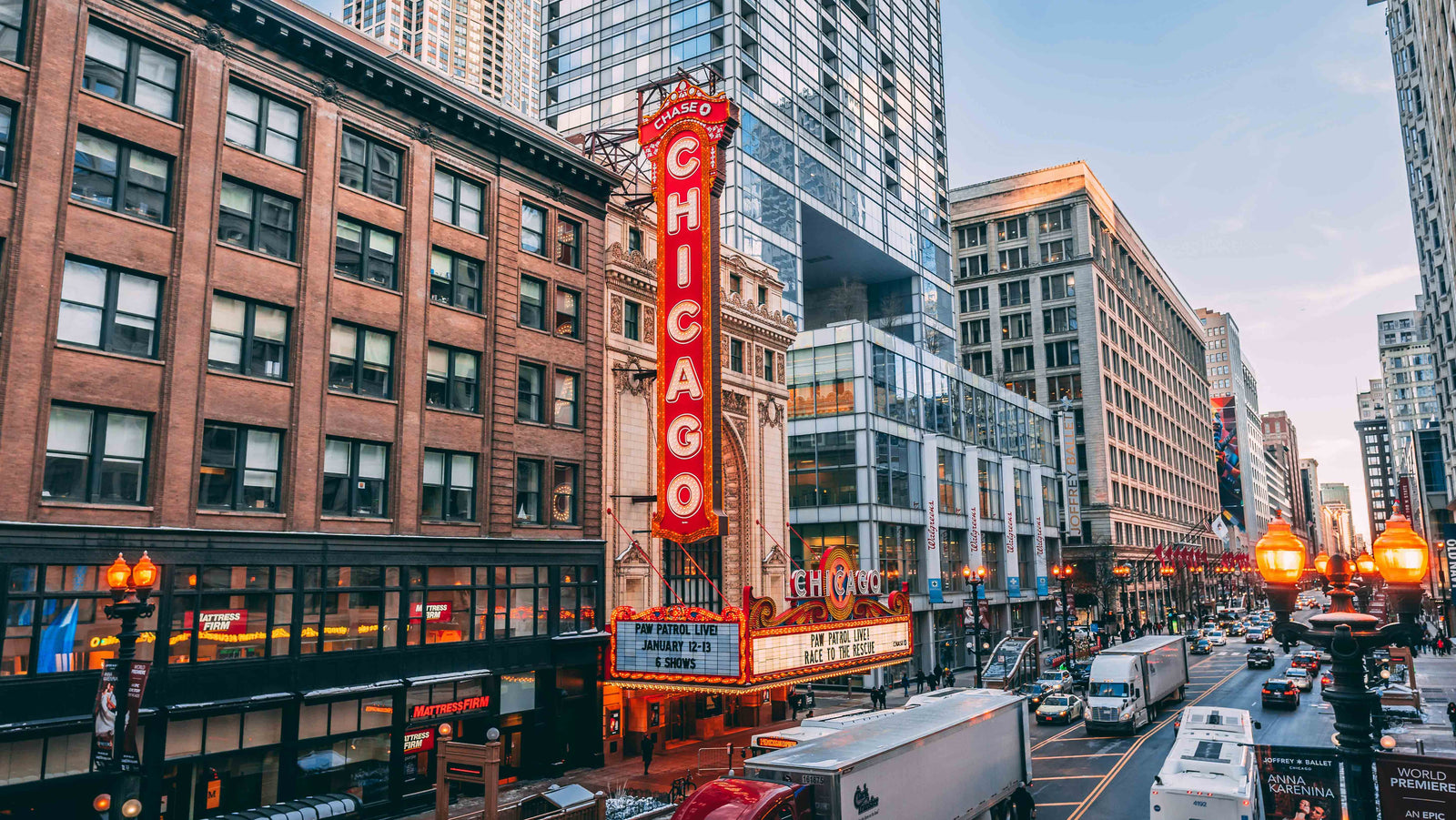 Chicago Downtown mit legendärem „CHICAGO“ Theater‑Schild an der State Street, historische Fassaden und dichter Stadtverkehr bei Abendlicht.﻿
