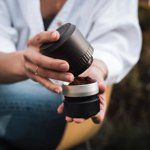 OutIn Fino Kaffeemühle: Frisch gemahlener Kaffee fällt aus der schwarzen Mühle in den silbernen Auffangbehälter.