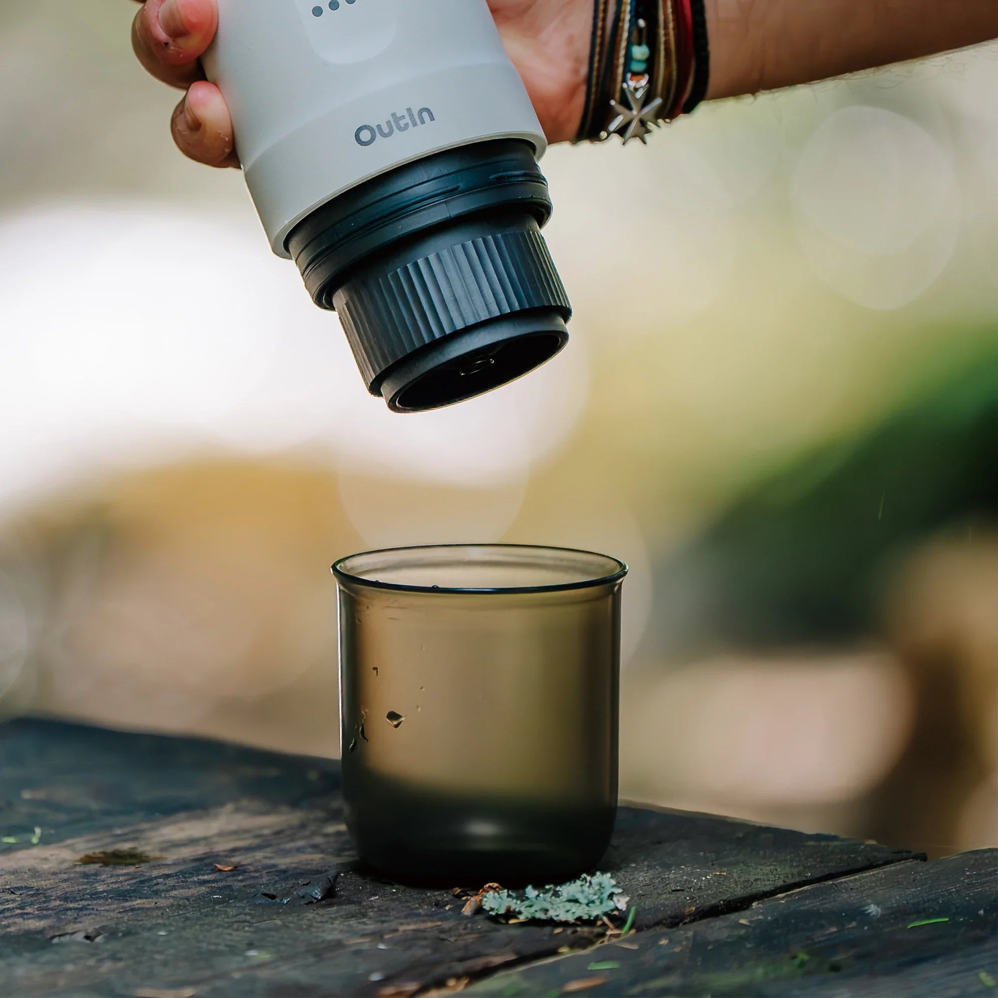 Hand holding dark espresso cup with Nano Portable Espresso Machine above for brewing outdoors.
